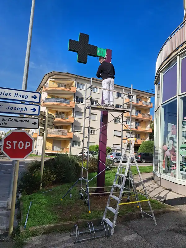 Peintre de RUSHITI Rénovation sur échafaudage roulant, repeignant le poteau de la croix de la Pharmacie Gillet à Besançon
